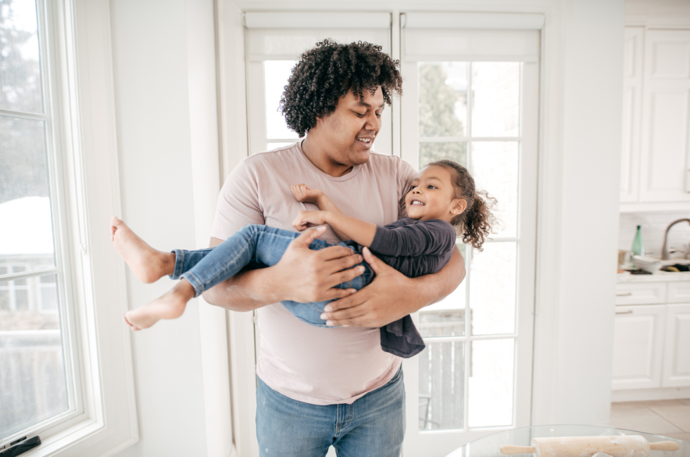 A parent holding their child in their arms, smiling at each other.