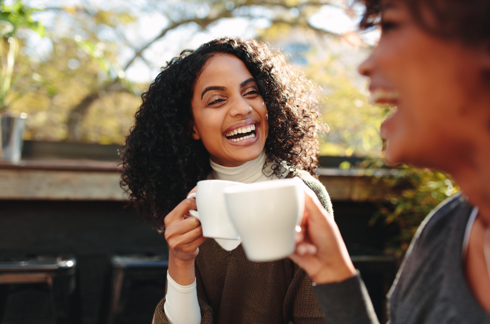 Woman looking at her friend while they both hold a cup of coffee
