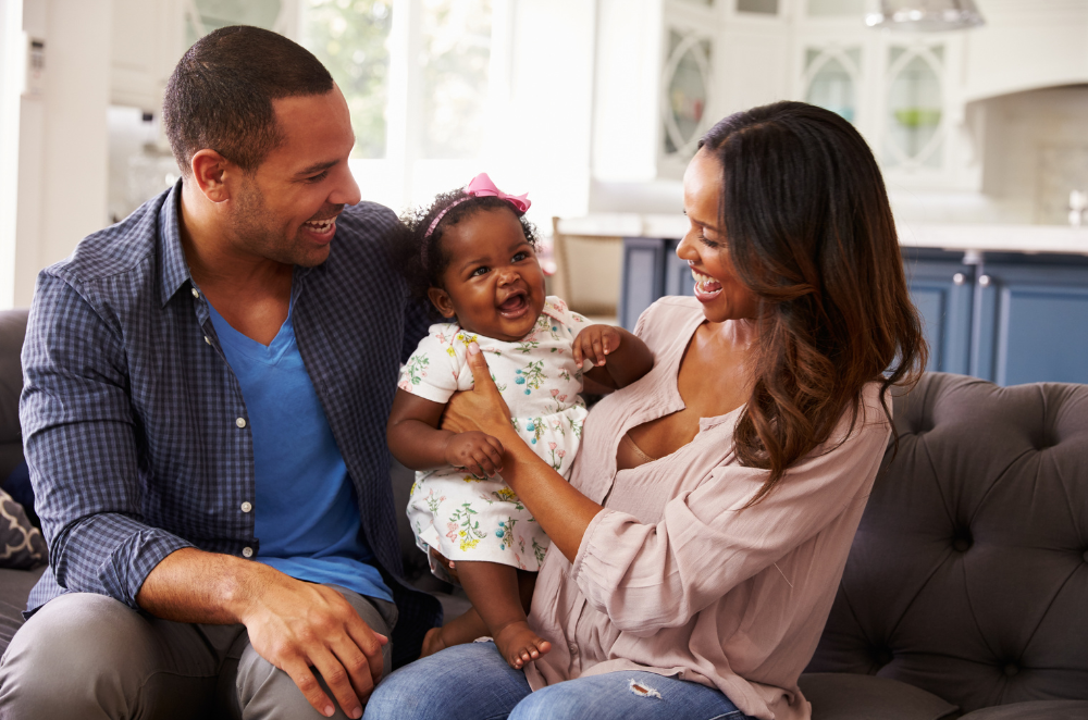 Parents sitting on the couch holding their baby